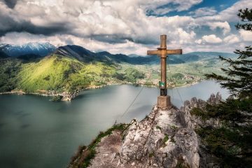 brown cross near body of water under white sky